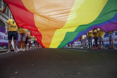 Londra, Ingiltere-6 Temmuz 2019: Insanlar Londra gurur olayın başlangıcında büyük bir LGBTQ gay gurur gökkuşağı bayrağı tutun