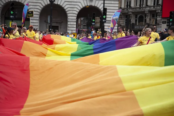 Londra, Ingiltere-6 Temmuz 2019: Insanlar Londra gurur olayın başlangıcında büyük bir LGBTQ gay gurur gökkuşağı bayrağı tutun — Stok fotoğraf