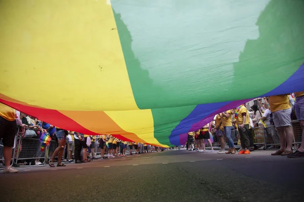 Londra, Ingiltere-6 Temmuz 2019: Insanlar Londra gurur olayın başlangıcında büyük bir LGBTQ gay gurur gökkuşağı bayrağı tutun
