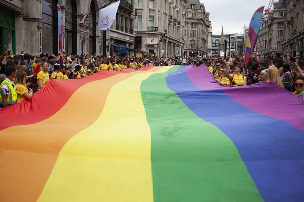 Londra, Ingiltere-6 Temmuz 2019: Insanlar Londra gurur olayın başlangıcında büyük bir LGBTQ gay gurur gökkuşağı bayrağı tutun — Stok fotoğraf