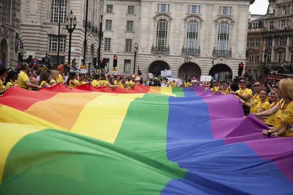 LONDRES, Reino Unido - 6 de julio de 2019: La gente sostiene una enorme bandera del arco iris del orgullo gay LGBTQ al comienzo del evento del orgullo de Londres — Foto de Stock