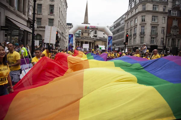 Londyn, Wielka Brytania-6 lipca 2019: ludzie posiadają ogromną flagę LGBTQ Gay dumy tęczy na początku imprezy dumy londyńskiej — Zdjęcie stockowe