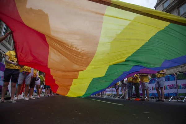 LONDRES, Reino Unido - 6 de julio de 2019: La gente sostiene una enorme bandera del arco iris del orgullo gay LGBTQ al comienzo del evento del orgullo de Londres — Foto de Stock