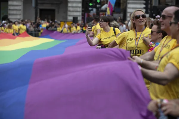 LONDRES, Reino Unido - 6 de julio de 2019: La gente sostiene una enorme bandera del arco iris del orgullo gay LGBTQ al comienzo del evento del orgullo de Londres —  Fotos de Stock