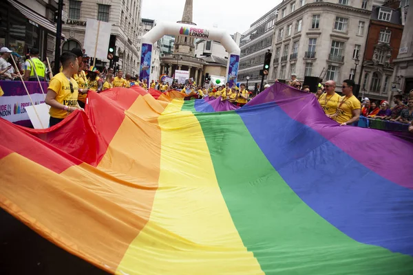 伦敦,英国 - 2019年7月6日:人们在伦敦骄傲活动开始时举着一面巨大的Lgbtq同性恋骄傲彩虹旗 — 图库照片