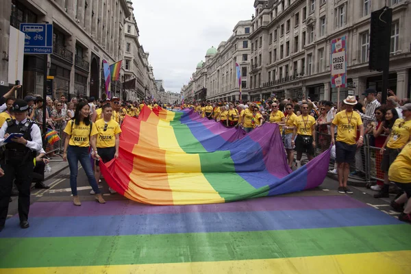 ЛОНДОН, Великобритания - 6 июля 2019 года: Люди держат огромный радужный флаг гей-прайда ЛГБТК в начале церемонии гордости Лондона — стоковое фото