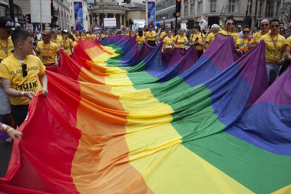 伦敦,英国 - 2019年7月6日:人们在伦敦骄傲活动开始时举着一面巨大的Lgbtq同性恋骄傲彩虹旗 — 图库照片