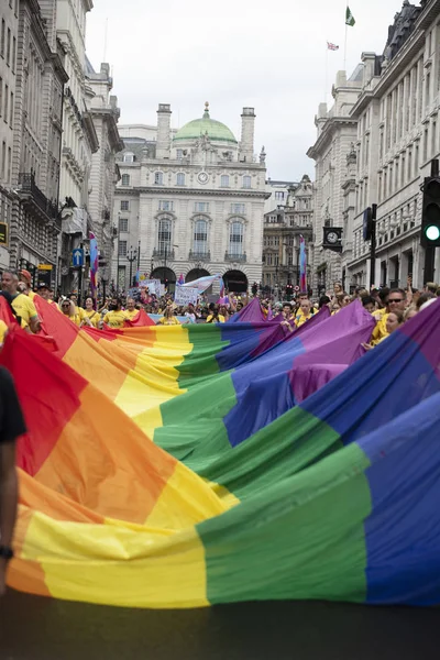 Лондон, Великобританія-6 липня 2019: люди тримають величезний ЛГБТ-гей прапор веселки на початку події Лондонської гордості — стокове фото
