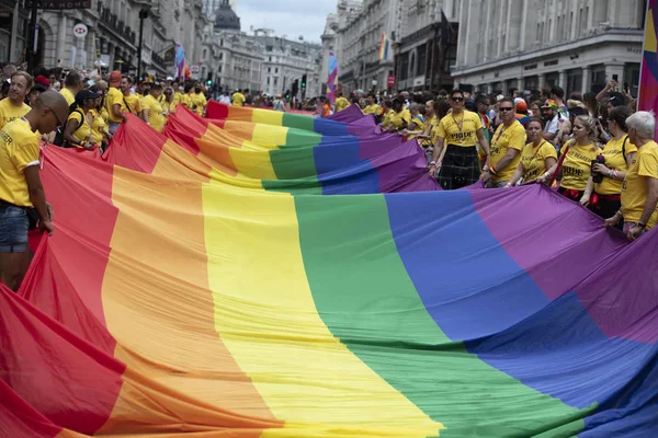Londra, Ingiltere-6 Temmuz 2019: Insanlar Londra gurur olayın başlangıcında büyük bir LGBTQ gay gurur gökkuşağı bayrağı tutun — Stok fotoğraf