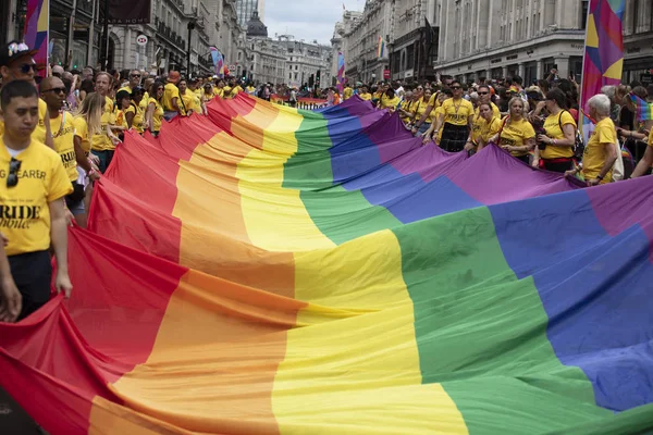 LONDRES, Reino Unido - 6 de julho de 2019: As pessoas seguram uma enorme bandeira LGBTQ do orgulho gay no início do evento de orgulho de Londres — Fotografia de Stock