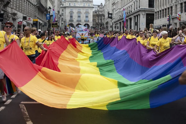 Londra, Ingiltere-6 Temmuz 2019: Insanlar Londra gurur olayın başlangıcında büyük bir LGBTQ gay gurur gökkuşağı bayrağı tutun — Stok fotoğraf