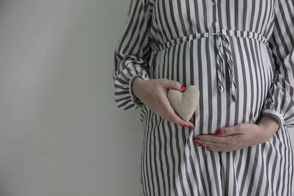 Una donna incinta che tiene una forma di cuore davanti a questo pancione — Foto Stock