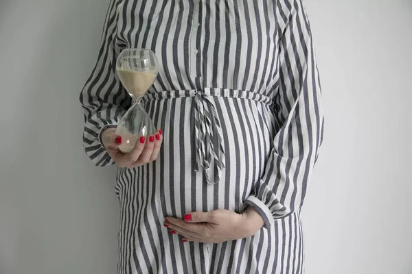 Pojęcie termin ciąży. Kobieta trzyma prgnant brzuch z zegarem jaj — Zdjęcie stockowe
