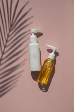 Tropikal palmiye yaprağı gölgesi ile pembe bir arka plan üzerinde şişekozmetik ürünler