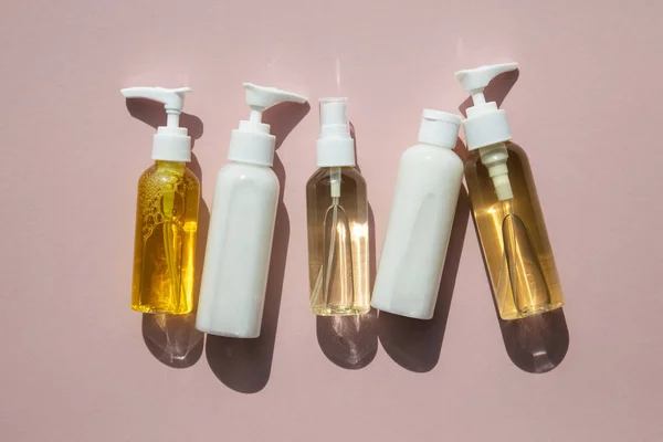 Une collection de produits cosmétiques de beauté en flacons clairs sur fond rose — Photo