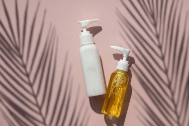 Tropikal palmiye yaprağı gölgesi ile pembe bir arka plan üzerinde şişekozmetik ürünler