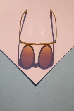 Pembe ve mavi arka plan üzerinde uzun gölge ile Fasionable yaz güneş gözlüğü
