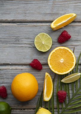 Yaratıcı meyveler düz yatıyordu. Ahşap arka planda turuncu, kireç ve ahududu