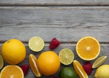 Yaratıcı meyveler düz yatıyordu. Ahşap arka planda turuncu, kireç ve ahududu