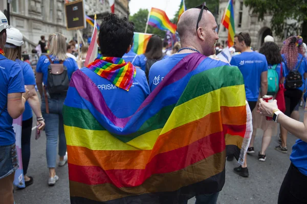 Londra, İngiltere - 6 Temmuz 2019: Londra'nın merkezinde her yıl düzenlenen eşcinsel gurur yürüyüşüne eşcinsel gurur bayrağına sarılı iki adam katıldı — Stok fotoğraf