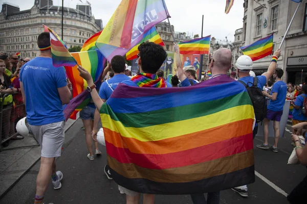 LONDRES, Reino Unido - 6 de julho de 2019: Dois homens envolvidos em uma bandeira de orgulho gay participam da marcha anual do orgulho gay no centro de Londres — Fotografia de Stock