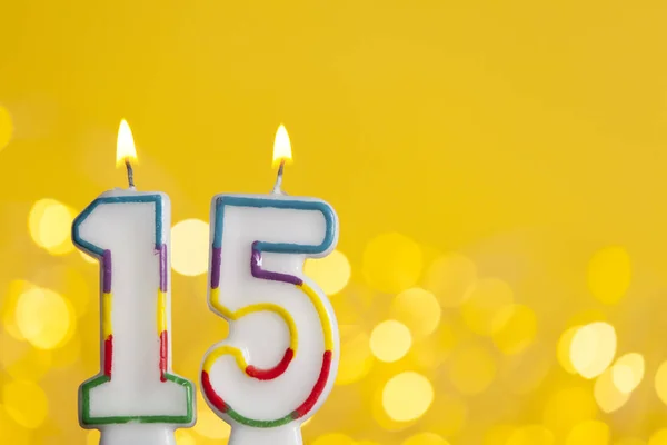 Number 15 birthday celebration candle against a bright lights an — Stock Photo, Image