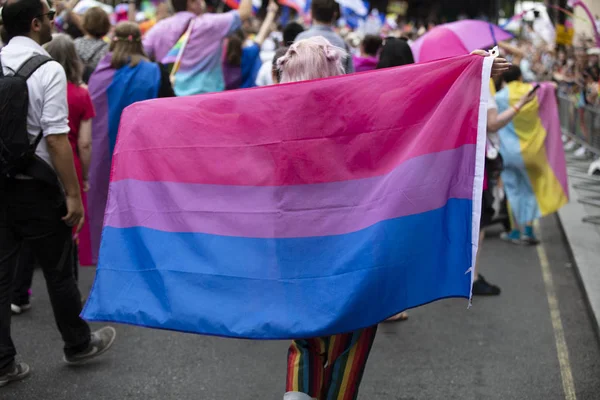 Londen, VK-6 juli 2019: een persoon zwedeert een biseksuele trots vlag op een Gay Pride maart in Londen — Stockfoto