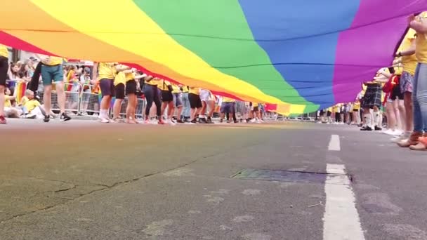 LONDRES, Reino Unido - 6 de julio de 2019: La gente sostiene una enorme bandera del arco iris del orgullo gay LGBTQ al comienzo del evento del orgullo de Londres — Vídeo de stock