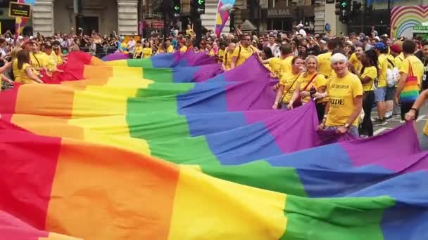 Londyn, Wielka Brytania-6 lipca 2019: ludzie posiadają ogromną flagę LGBTQ Gay dumy tęczy na początku imprezy dumy londyńskiej — Wideo stockowe