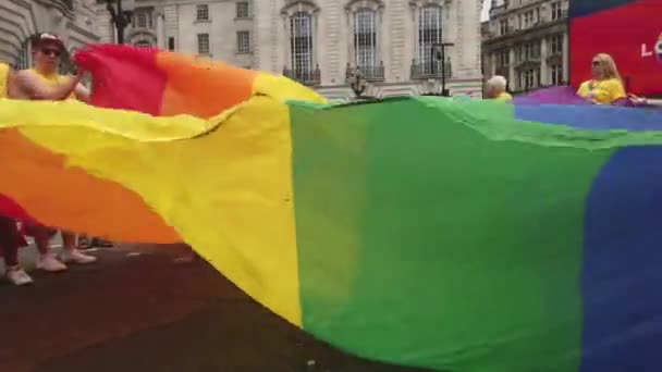 ЛОНДОН, Великобритания - 6 июля 2019 года: Люди держат огромный радужный флаг гей-прайда ЛГБТК в начале церемонии гордости Лондона — стоковое видео