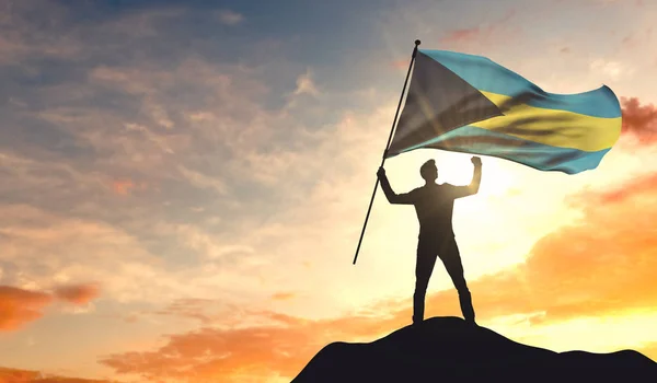 Η σημαία των Μπαχάμες χαιρετά έναν άντρα που γιορτάζει την επιτυχία στην κορυφή — Φωτογραφία Αρχείου