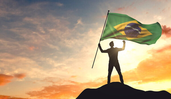 Флаг Бразилии размахивает человеком, празднующим успех на вершине
 