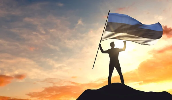 Bandera de Estonia ondeada por un hombre que celebra el éxito en la cima — Foto de Stock