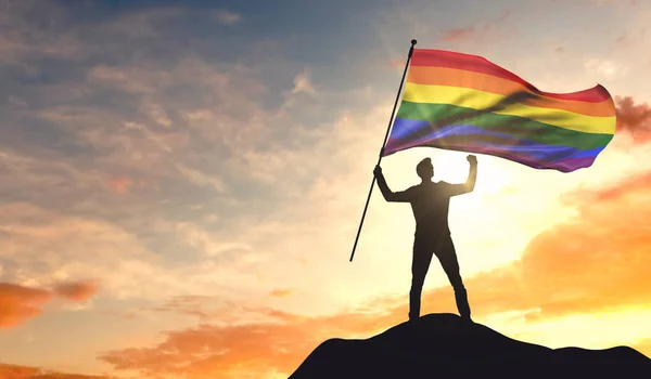 Gay orgullo bandera siendo ondeado por un hombre celebrando el éxito en el t —  Fotos de Stock