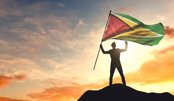 Bandera de Guyana ondeada por un hombre que celebra el éxito en la cima —  Fotos de Stock