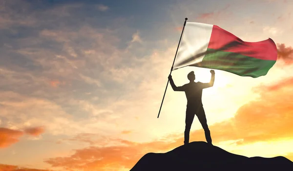 Madagascar flag being waved by a man celebrating success at the — Stock Photo, Image