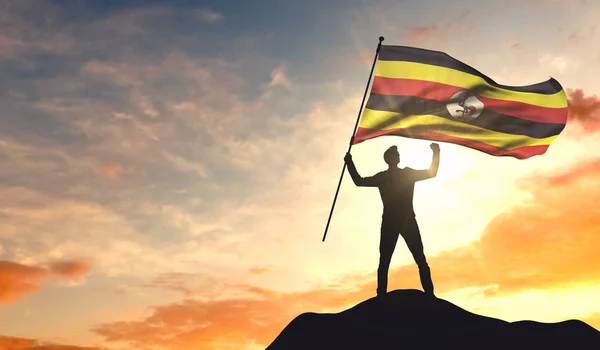 Bandiera Uganda sventolata da un uomo che celebra il successo in cima — Foto Stock