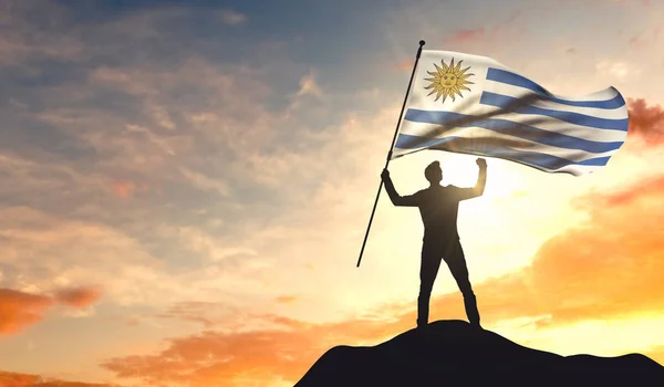 Bandera de Uruguay ondeada por un hombre que celebra el éxito en la cima —  Fotos de Stock