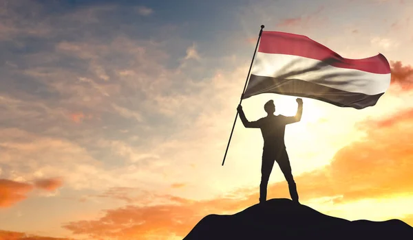 Bandeira do Iêmen sendo acenada por um homem comemorando o sucesso no topo do — Fotografia de Stock