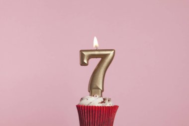 Pastel pembe backgrou karşı bir cupcake sayı 7 altın mum