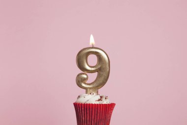 Pastel pembe backgrou karşı bir cupcake sayı 9 altın mum