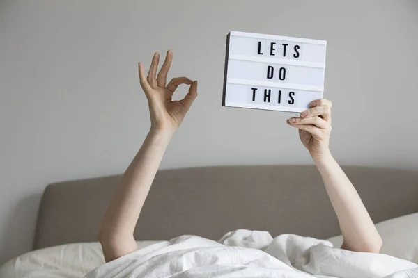 Female in bed under the sheets holding up a lets do this sign — Stock Photo, Image