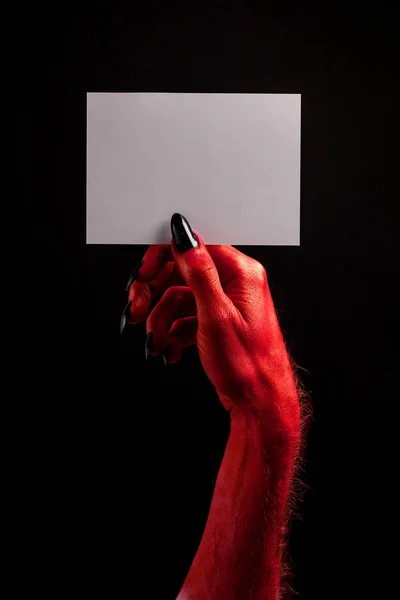 Rote Teufelshand, die ein leeres weißes Schild hält. Halloween-Konzept — Stockfoto