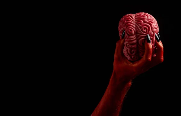 Mano roja del diablo sosteniendo un cerebro humano. Concepto Halloween — Foto de Stock