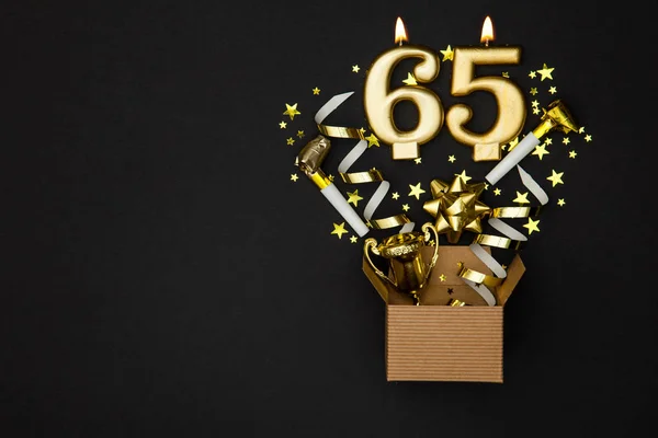 Number 65 gold celebration candle and gift box background — Stock Photo, Image