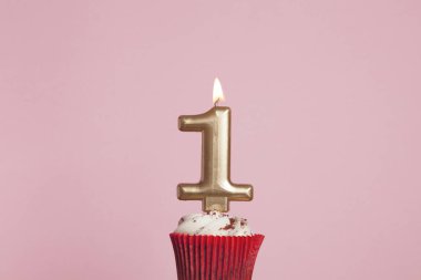 Pastel pembe backgrou karşı bir cupcake sayı 1 altın mum