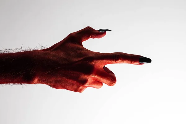 Halloween red devil monster hand with black fingernails against — Stock Photo, Image