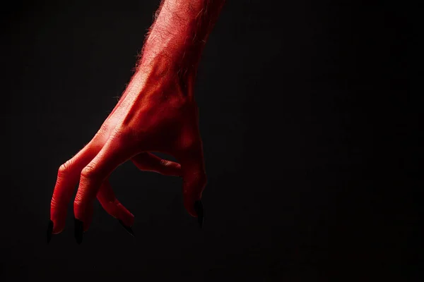 Red devil espeluznante mano de halloween sobre un fondo negro —  Fotos de Stock
