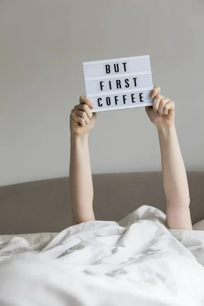 Mujer en la cama debajo de las sábanas sosteniendo un pero primer sig café — Foto de Stock