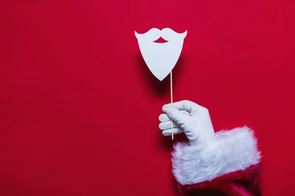 Санта Клаус Різдво рука тримає бороду проти Червоної backgro — стокове фото